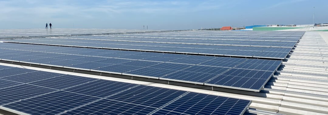Multiple rows of solar panels atop a commercial building roof